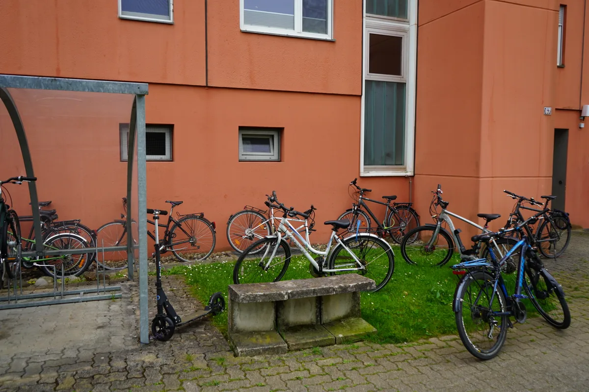 Man sieht Velos wild durcheinander vor einem Wohnblock.